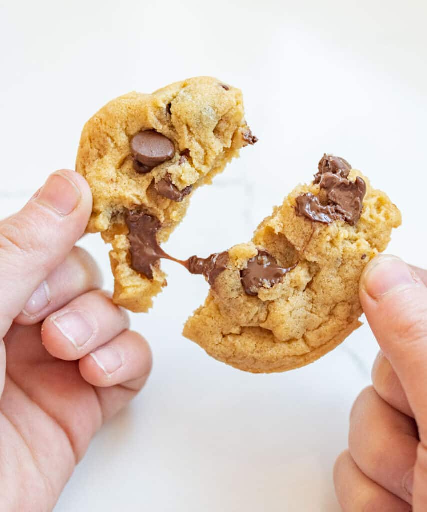 hands pulling apart a delicious chocolate chip cookie