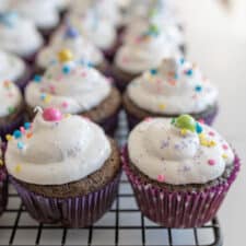 chocolate cupcakes with vanilla frosting and sprinkles on cooling rack