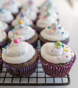 chocolate cupcakes with vanilla frosting and sprinkles on cooling rack