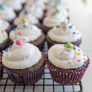 chocolate cupcakes with vanilla frosting and sprinkles on cooling rack