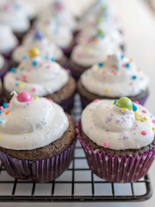 chocolate cupcakes with vanilla frosting and sprinkles on cooling rack