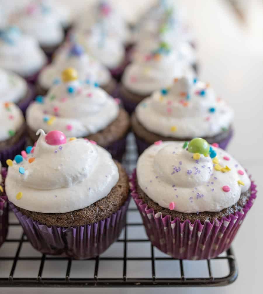 chocolate cupcakes with fluffy vanilla frosting and sprinkles on cooling rack