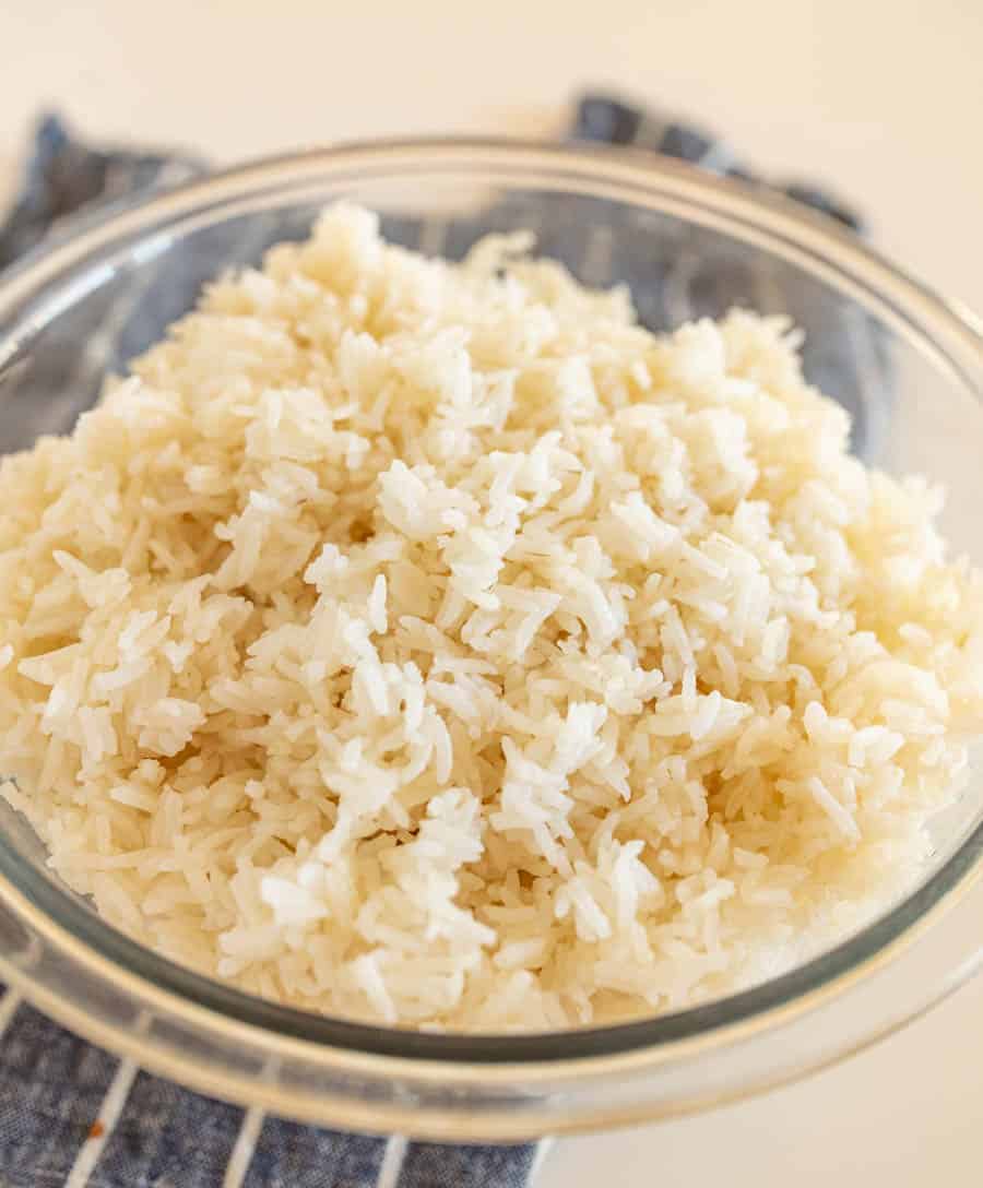 clear glass bowl of cooked white rice on blue and white striped towel