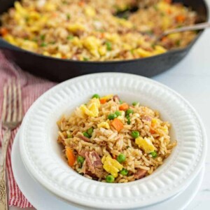 easy fried rice in a round white bowl next to skillet of fried rice