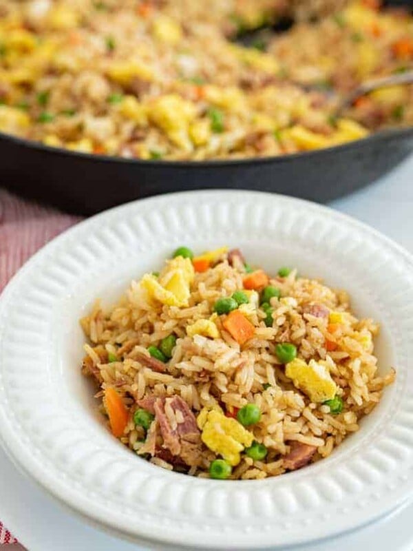 easy fried rice in a round white bowl next to skillet of fried rice