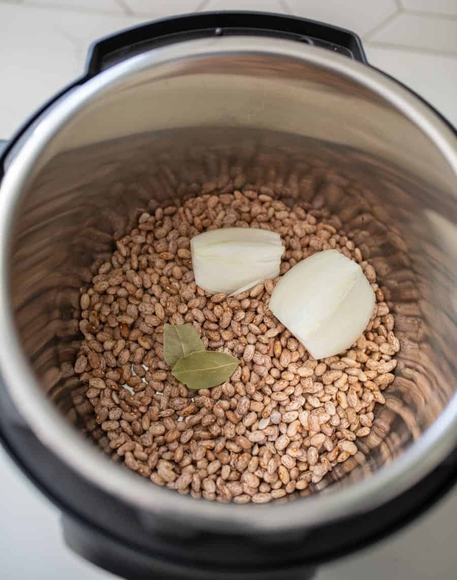 uncooked pinto beans with two pats of butter and two bay leaves