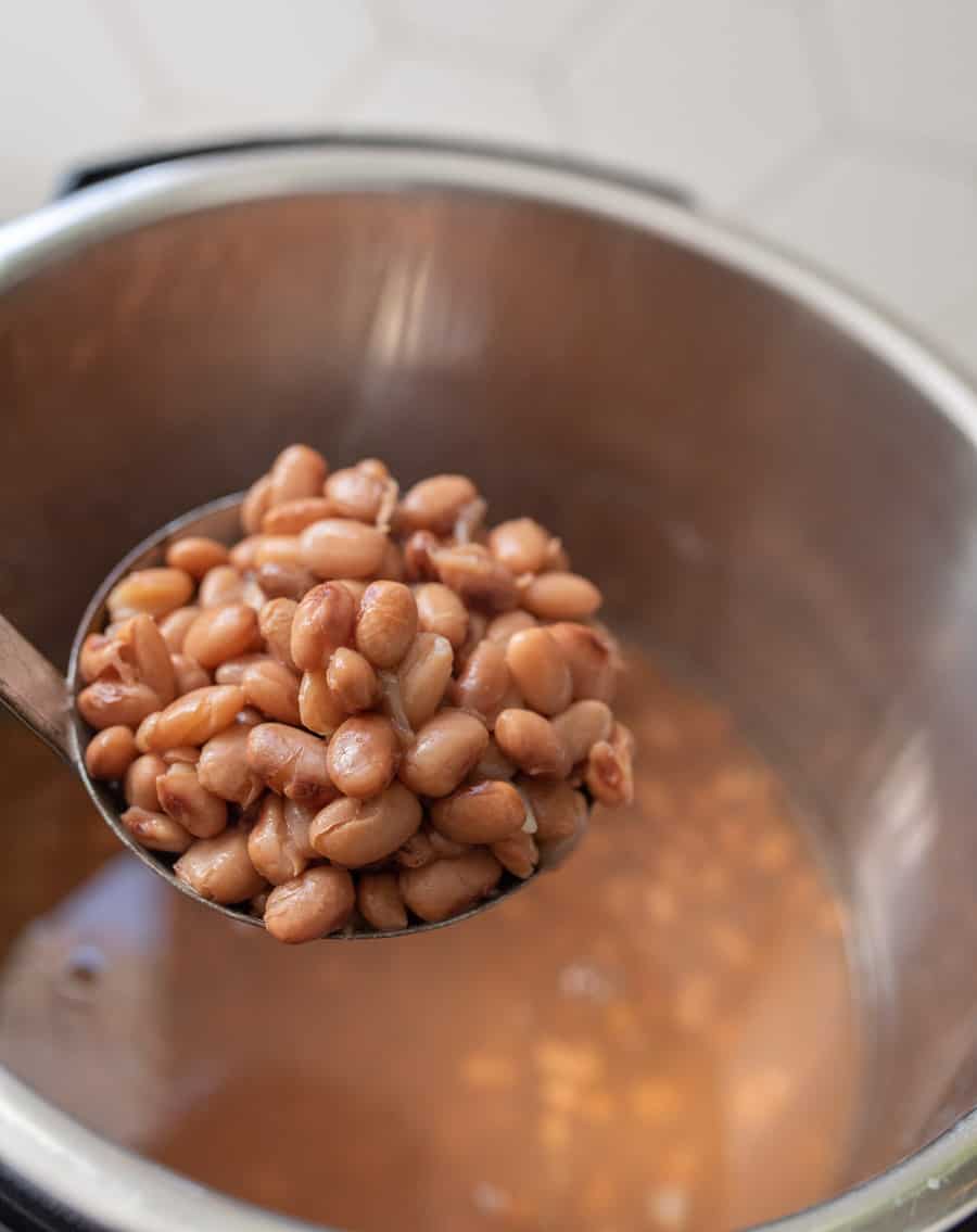 ladle full of cooked pinto beans held over instant pot filled with pinto beans