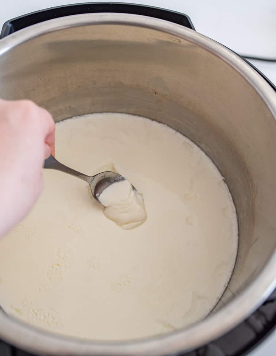 woman scooping yogurt with a spoon from the instant pot