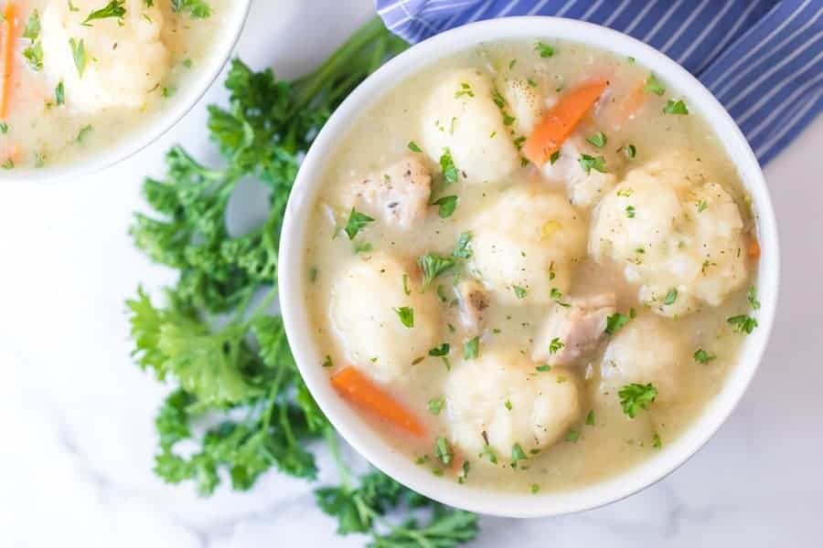 small white round bowl of chicken and dumplings soup