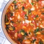 classic minestrone soup in round white bowl with blue rim