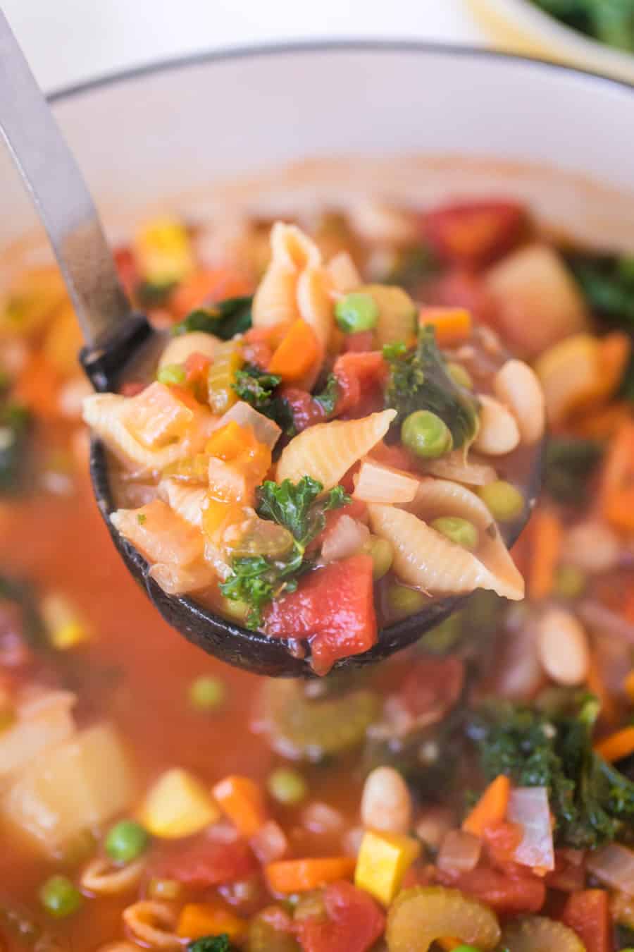 ladle filled with classic minestrone soup over a pot of soup