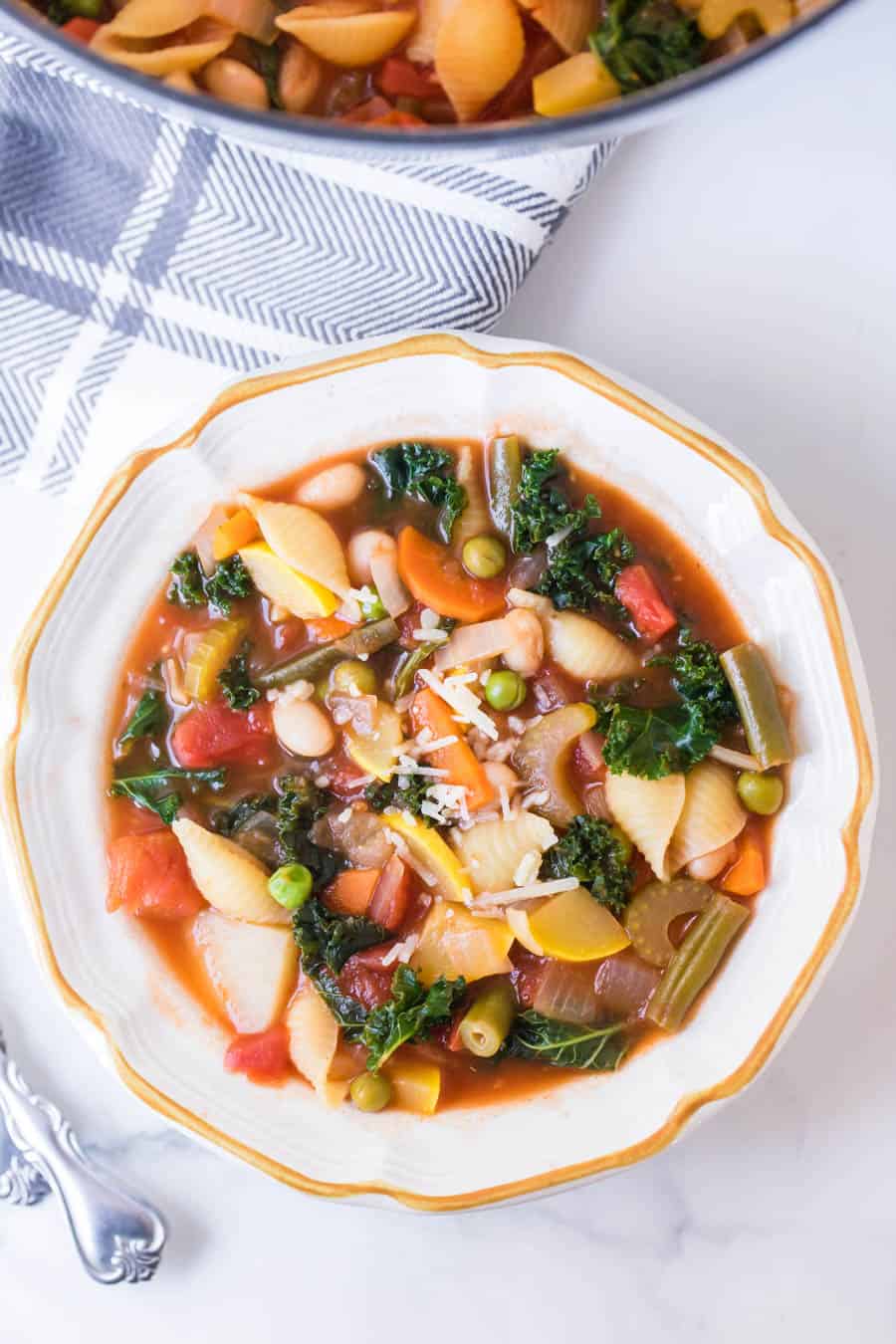 bowl of classic minestrone soup with spoons on blue checkered towel