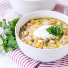 round white bowl with white bean chicken chili on red striped towel