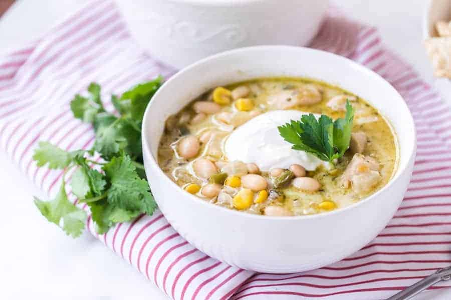 round white bowl with white bean chicken chili on red striped towel