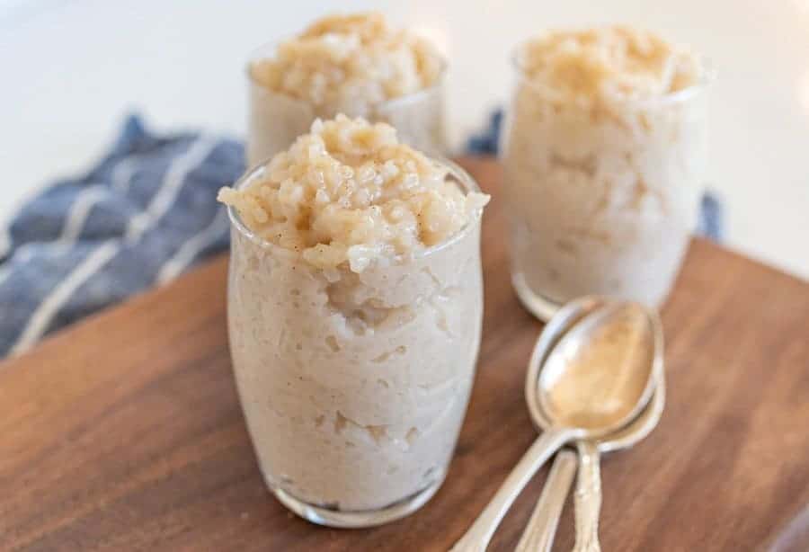 three spoons and three servings of rice pudding on cutting board