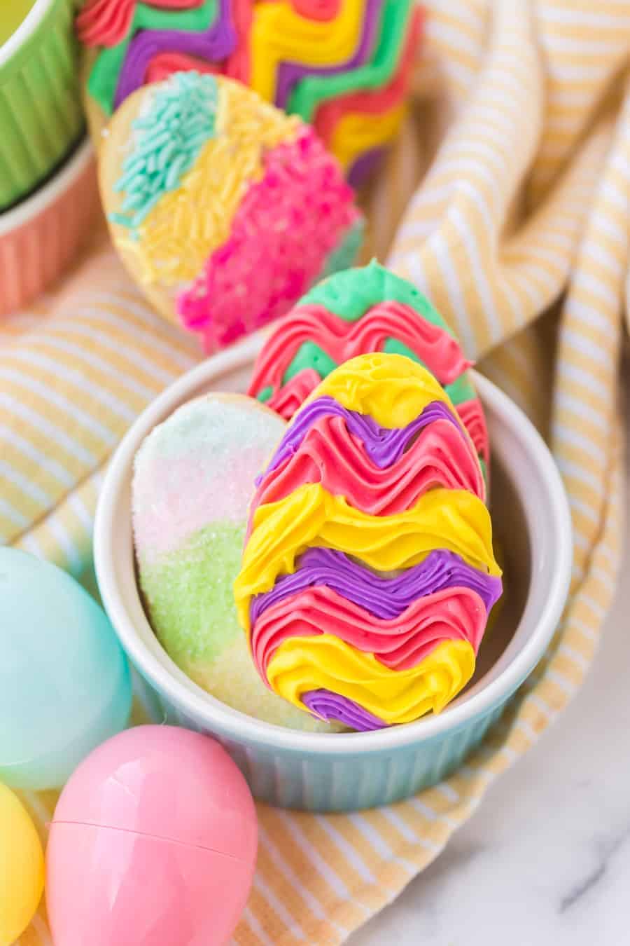 closeup of iced easter egg shaped sugar cookies in blue and white ramekin