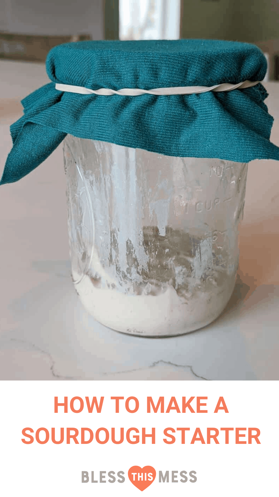sour dough starter in glass jar with blue cloth and rubberband covering top