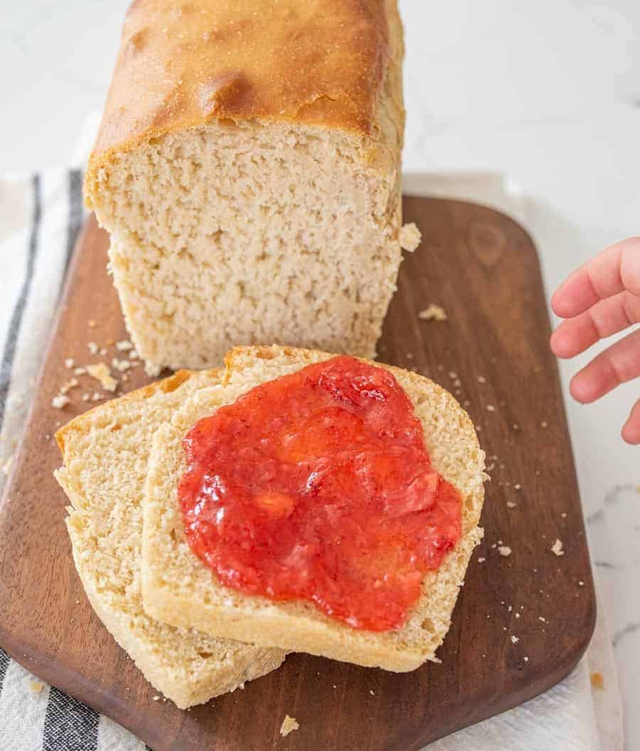 sourdough sandwich bread loaf with two slices cut with jam on cutting board