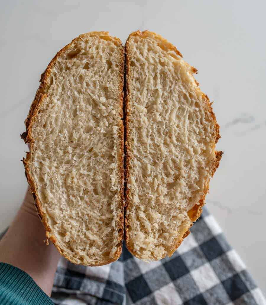 woman holding two slices of sourdough bread over black and white checkered towel.