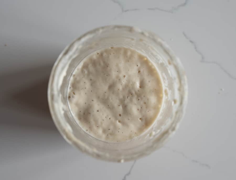 glass jar of sourdough on white countertop