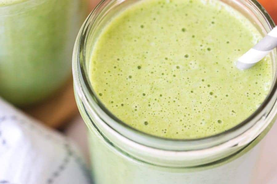 closeup of healthy green smoothie with gray and white paper straw