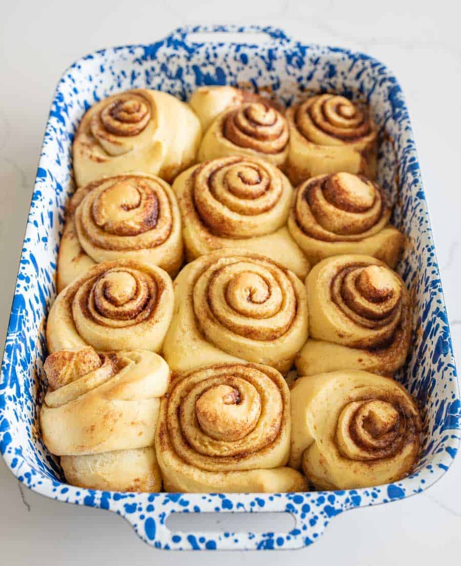 baked sourdough cinnamon rolls in blue and white baking pan