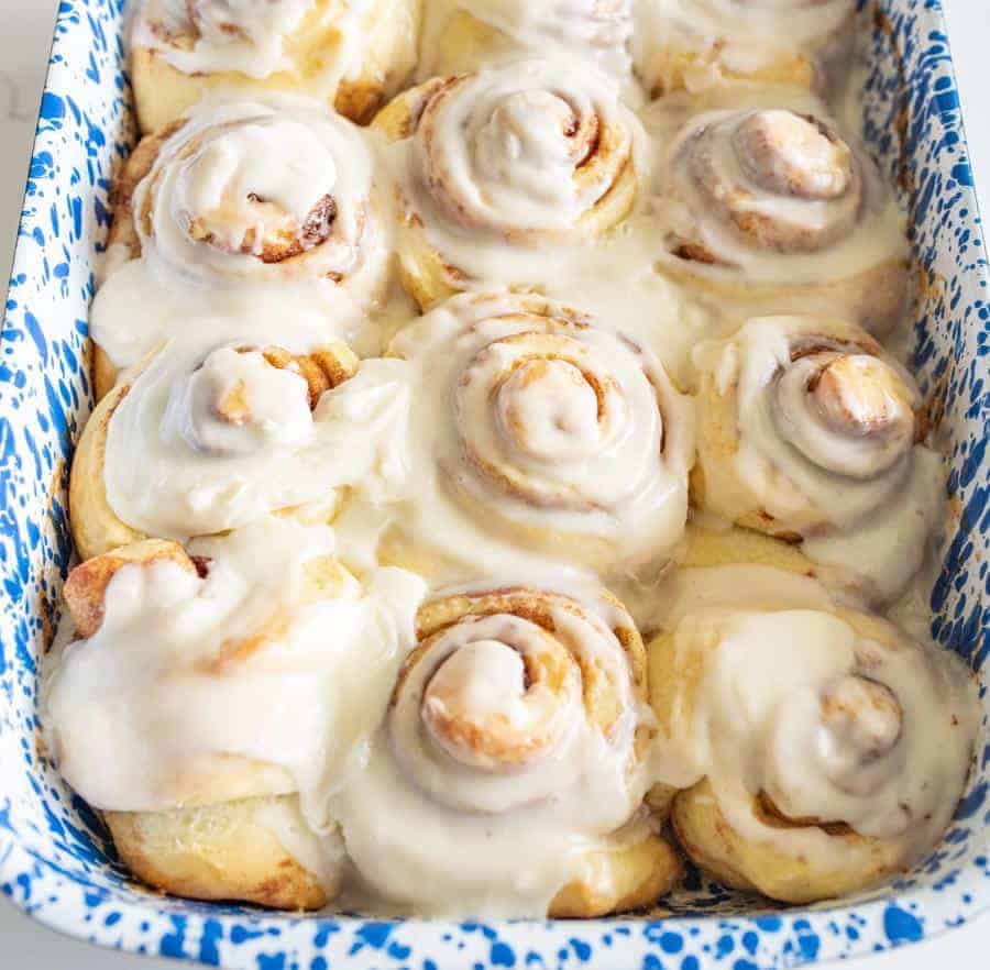 sourdough cinnamon rolls with buttercream icing in blue and white baking dish