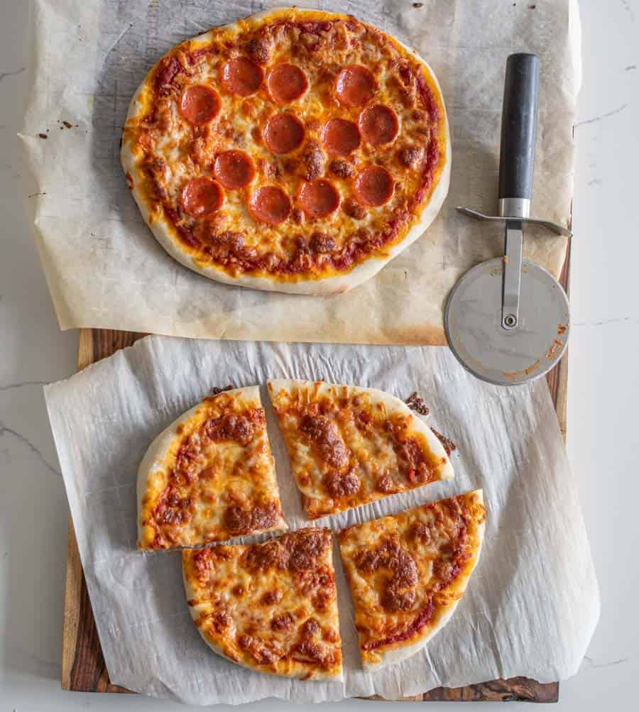 pepperoni sourdough pizza and cheese sourdough pizza on parchment with pizza cutter