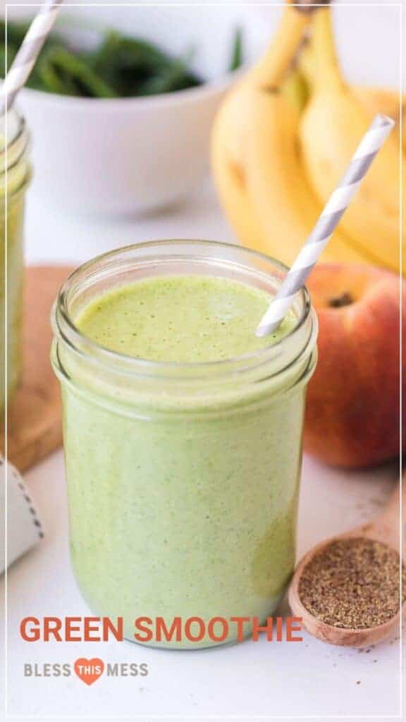 green smoothie in a mason jar with a paper straw