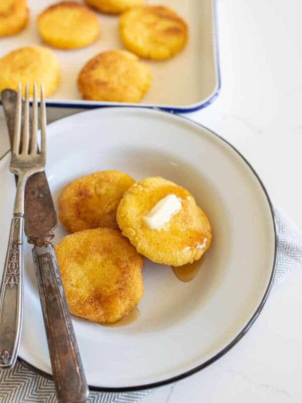 hot water cornbread with butter on white plate with knife and fork.