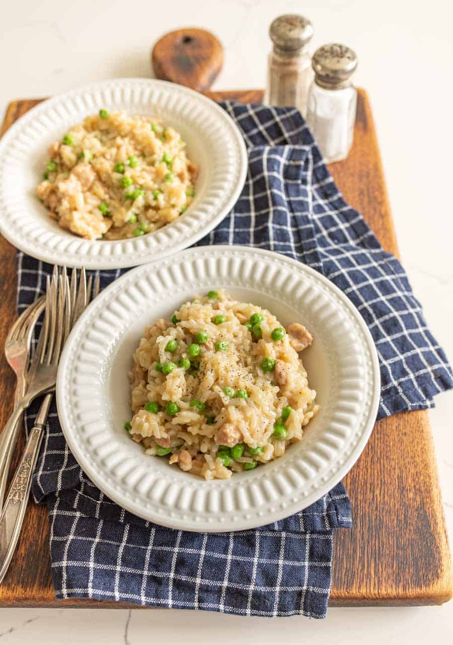 instant pot chicken and rice in white bowls on blue and white towel on cutting board with silverware