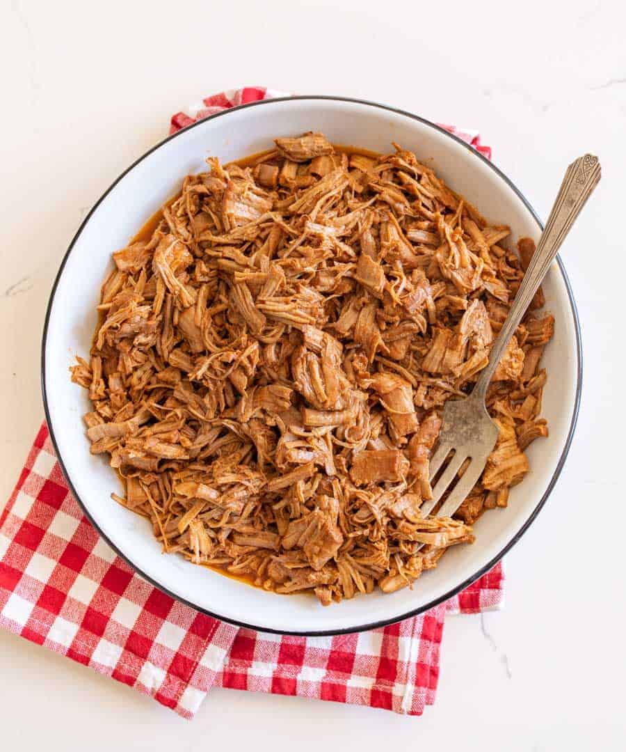 pulled pork on white serving platter with red check cloth