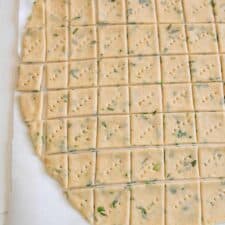 garlic and herb sourdough discard crackers on parchment before baking