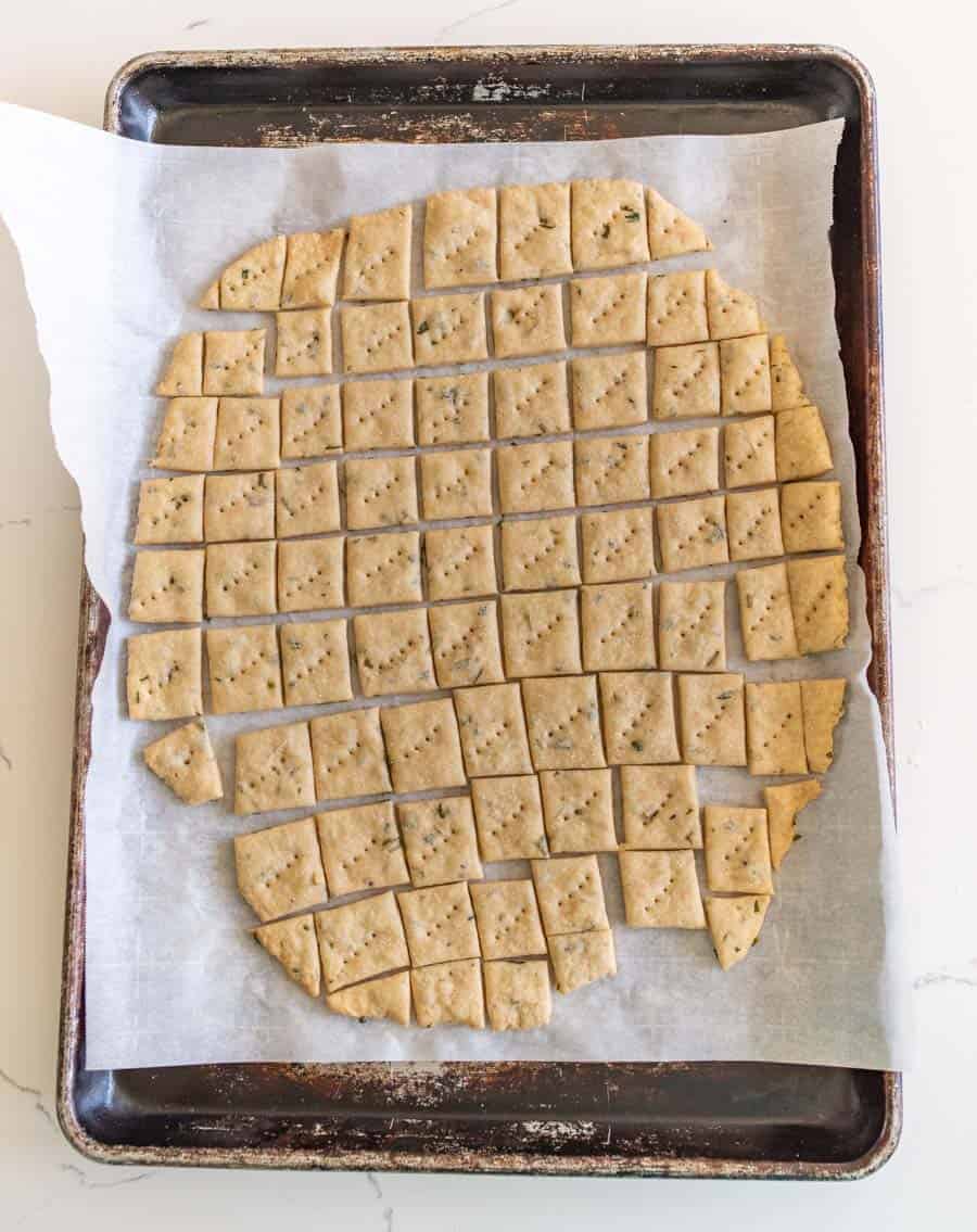 garlic and herb sourdough crackers on parchment on baking sheet