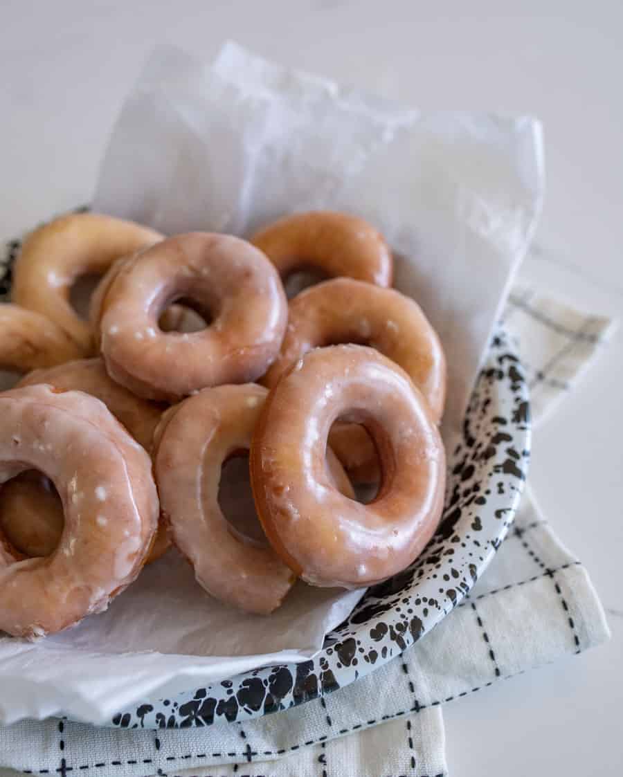 glazed donuts resting in a speckled serving dish