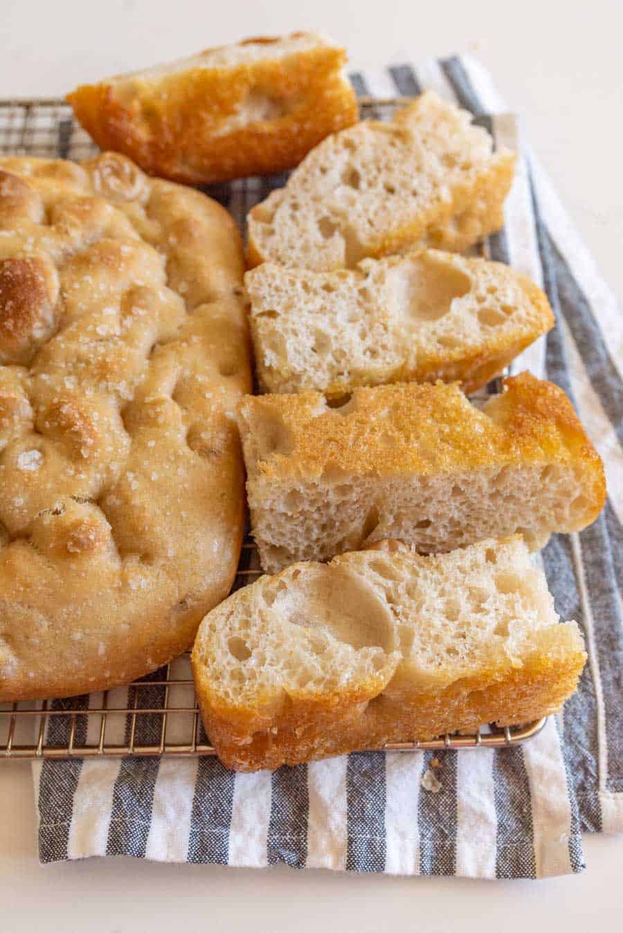 baked sourdough focaccia bread baked and sliced on cooling rack