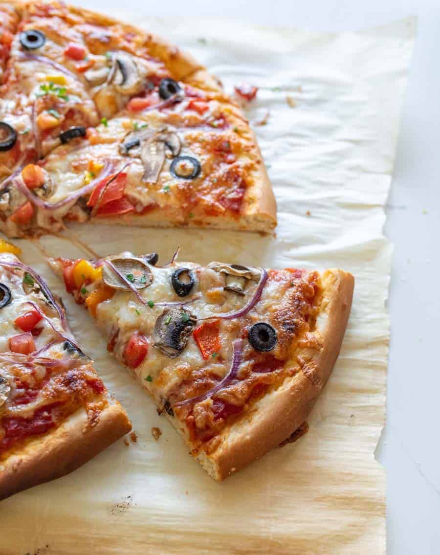 slice of veggie pizza pulled away from the pie closeup on parchment paper