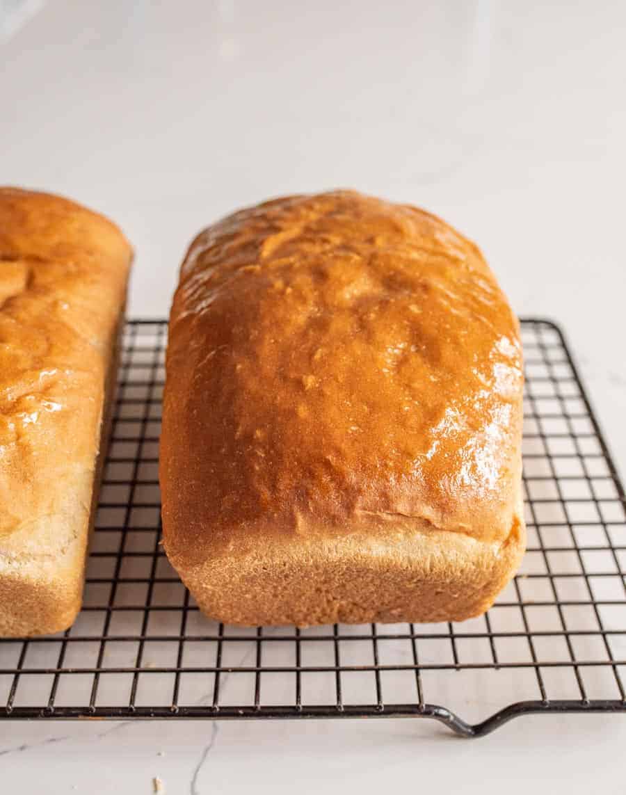 buttered loaf of bread on cooling rack