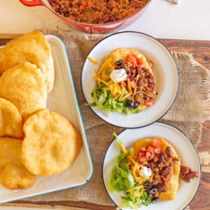 fry bread on plates made into Navajo tacos with lots of toppings