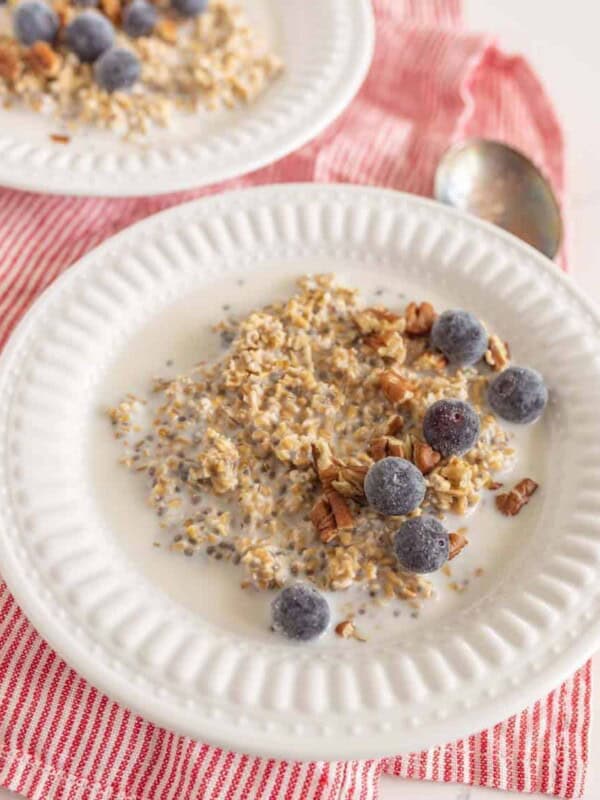 two white bowls of steel cut oats with fruit on red and white striped towel