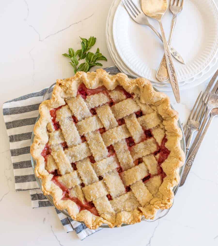 A top view of the latticed strawberry rhubarb pie with a stock of mint next to it.