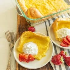 german pancakes cut and served on white plate with strawberries and whipped cream on top