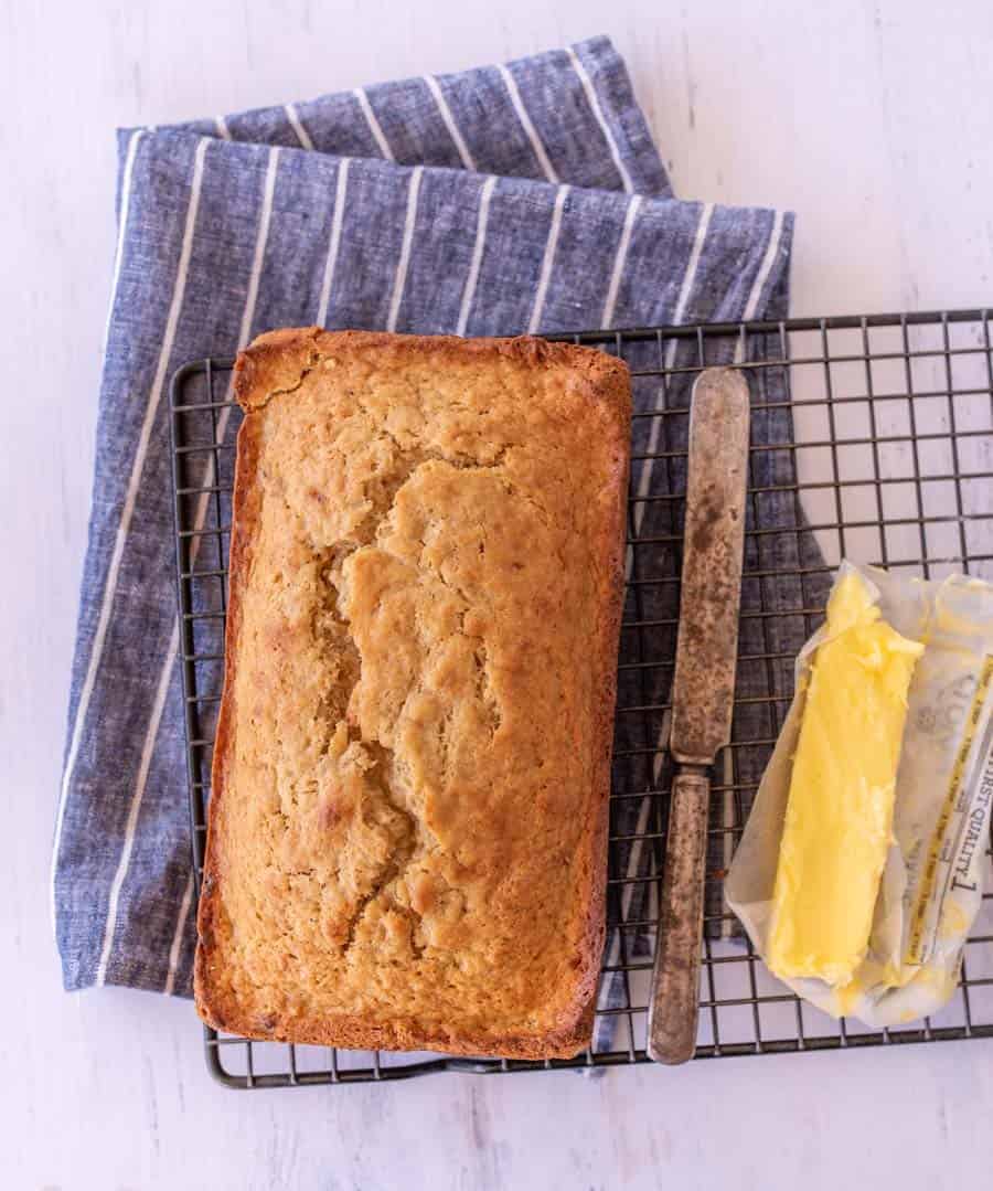 A whole baked banana bread sitting on cooling rack.