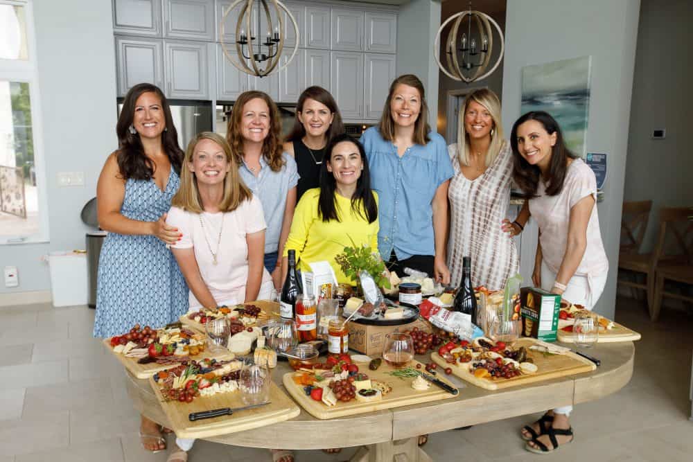women smiling around table of cheese