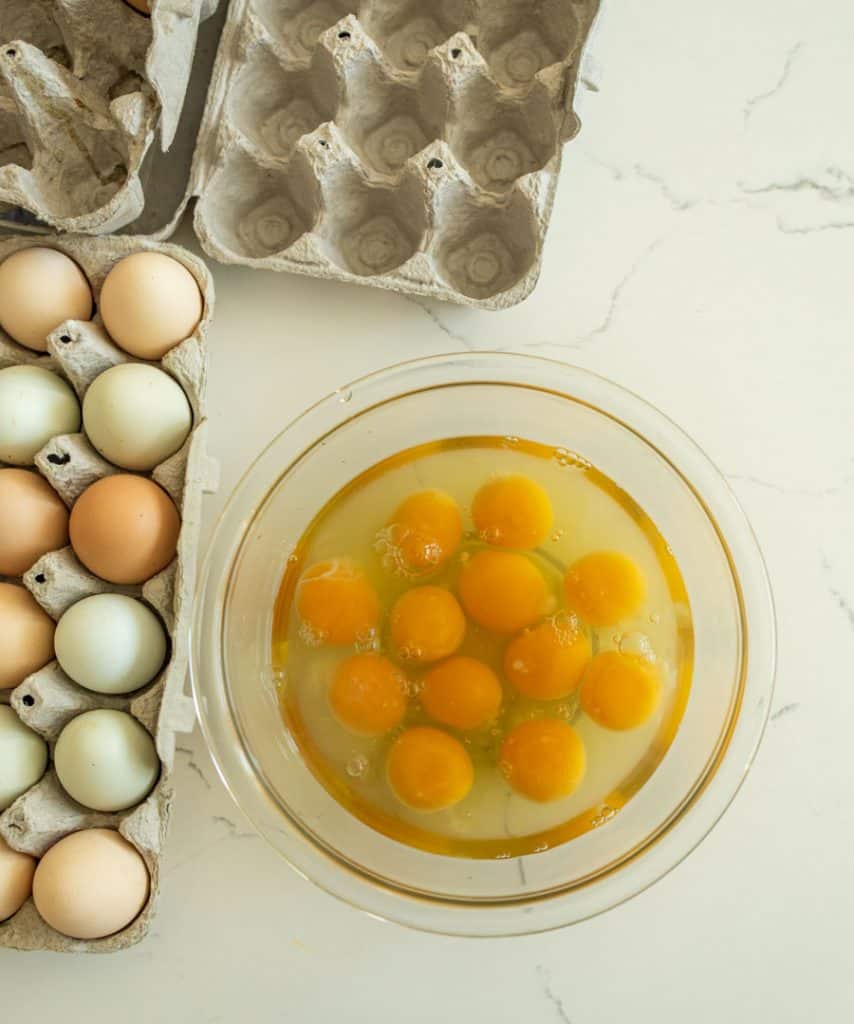 cracked raw eggs in a glass bowl