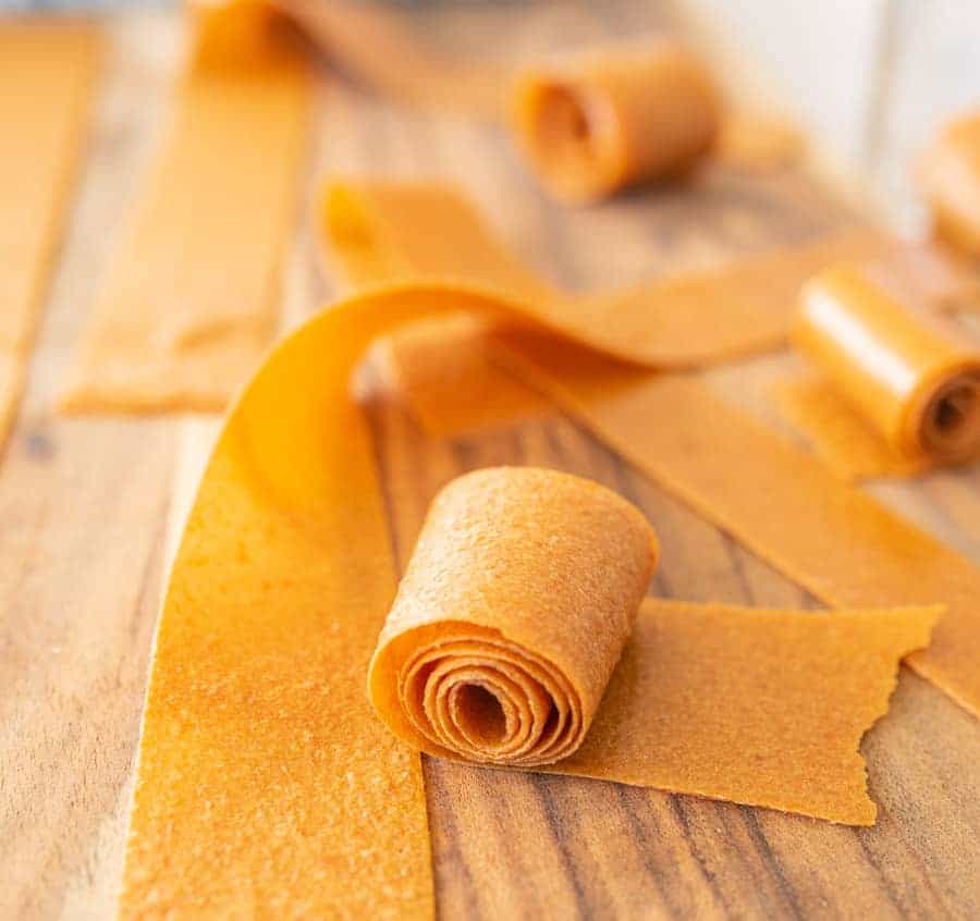 Rolled dried fruit leather in a yellowish orange hue.
