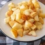crispy oven roasted potato cubes on enamel plate on gingham tablecloth