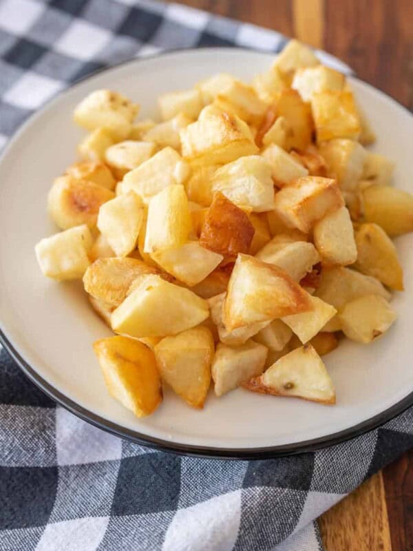 crispy oven roasted potato cubes on enamel plate on gingham tablecloth