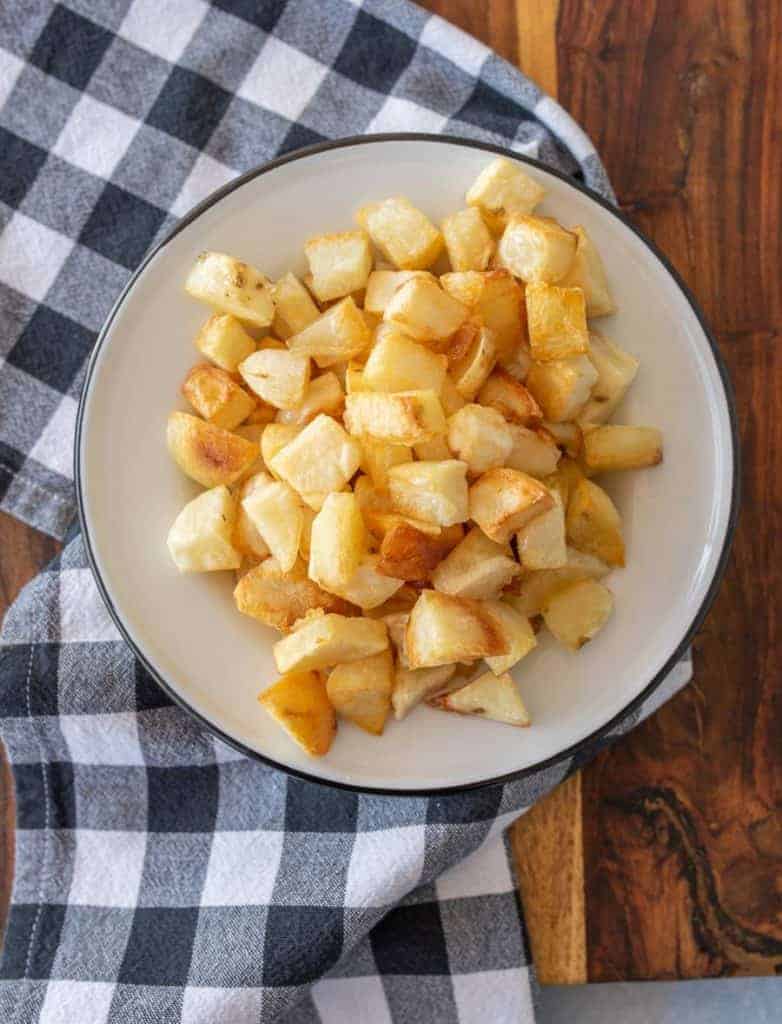 crispy oven roasted potato cubes on enamel plate on gingham tablecloth