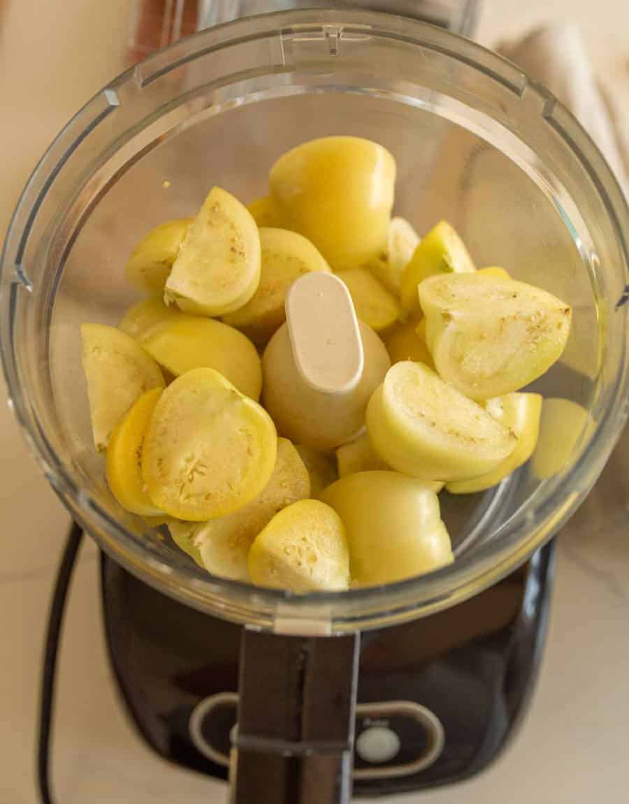 Quartered tomatillos in a food processor.
